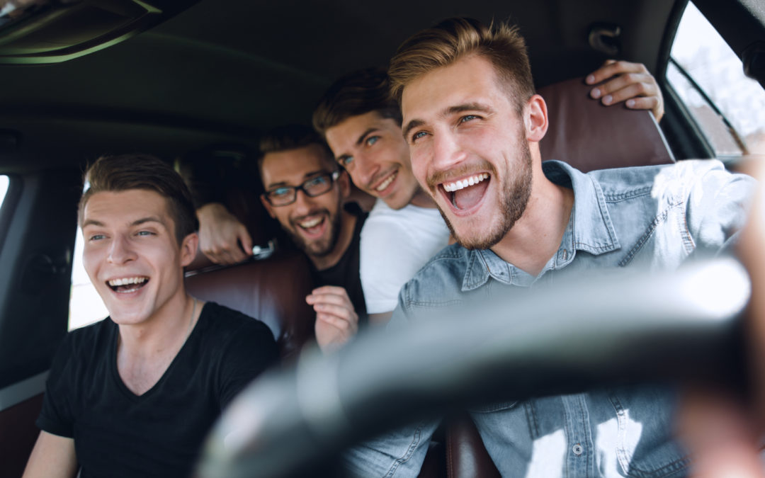 Un groupe de jeunes hommes tout sourire dans leur voiture de location